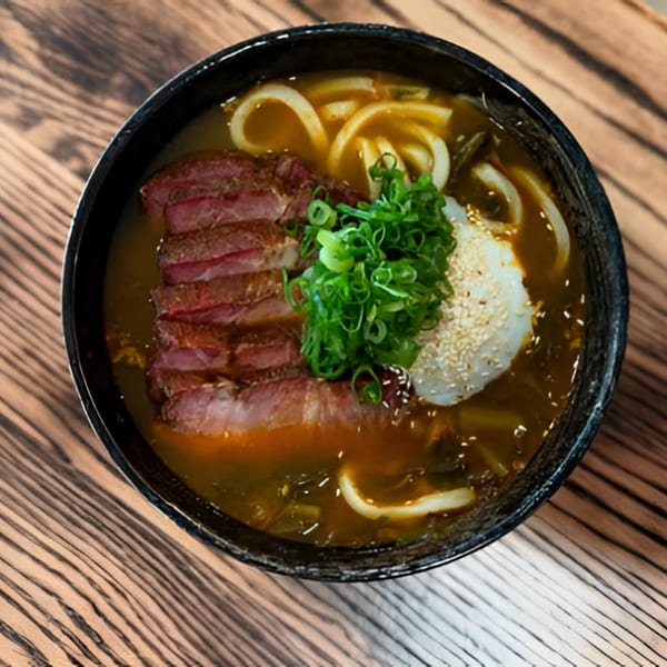 Bar Bushido's Japanese ramen with sliced beef, udon noodles, green onions, and a poached egg.