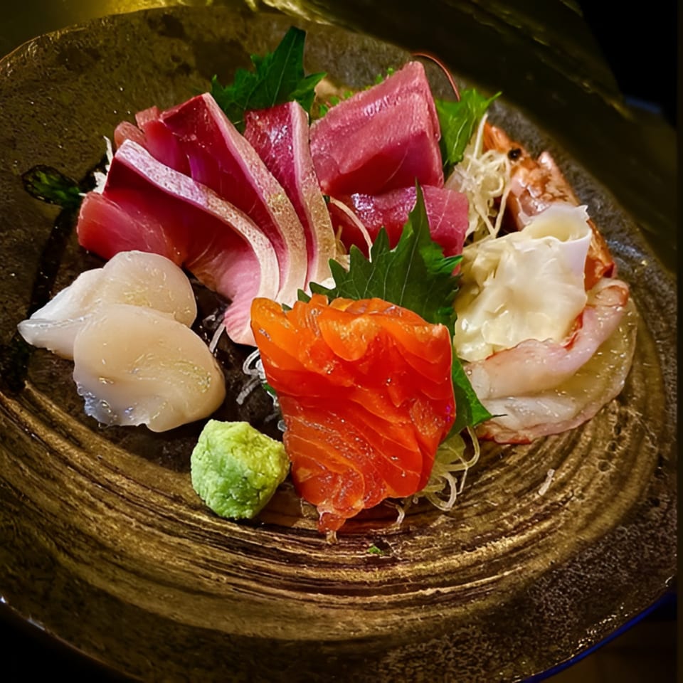 A close-up of a Bar Bushido sashimi platter with tuna, salmon, scallops, shrimp, and wasabi.